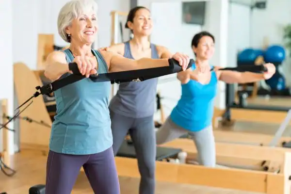 Toning Arms After 60: Empowering Womens Fitness Through Effective Weight Training 2 older woman doing weight training St Albans and resistance in the gym to tone upper arms