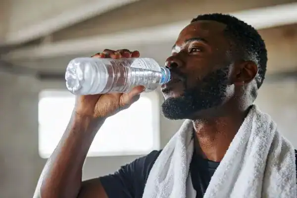 Image of man drinking water to improve hydration St Albans after work out.
